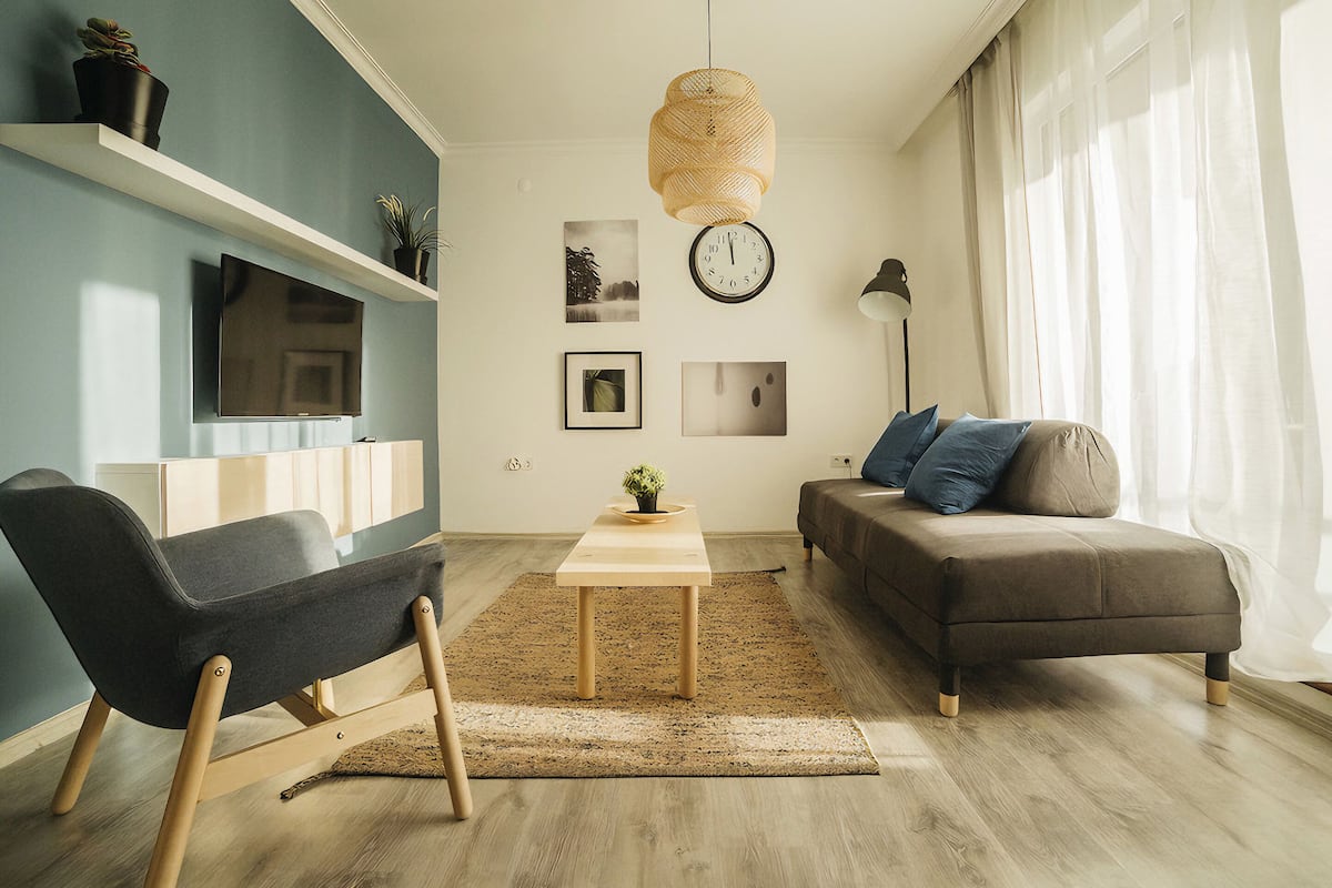 Una sala de estar moderna con un sofá, un sillón, una mesa de centro, un televisor y un reloj en la pared.