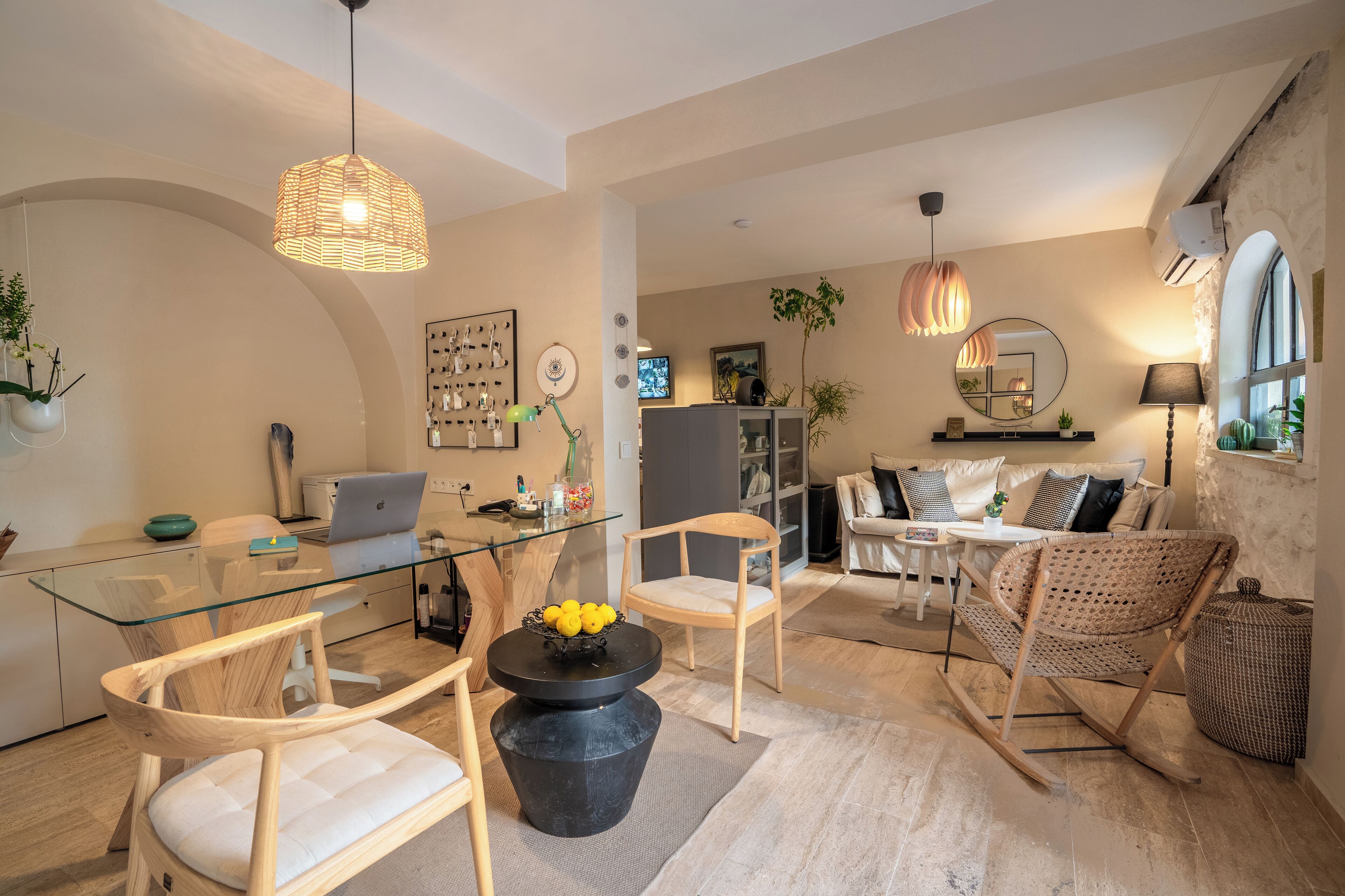 Un salón moderno con una mesa de vidrio, sillas de mimbre y una mesa baja negra con limones.