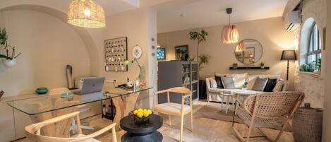 Un salon moderne avec une table à manger en verre, des chaises en osier et une table basse noire décorée de citrons.