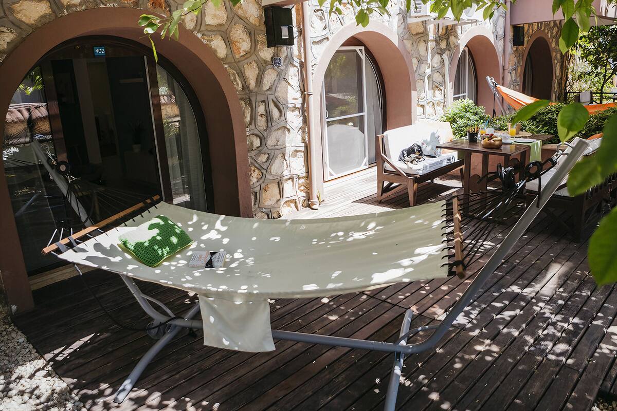 A hammock set up on a wooden deck with stone walls and arched doorways.