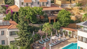 Uma villa com piscina, várias espreguiçadeiras e um jardim.