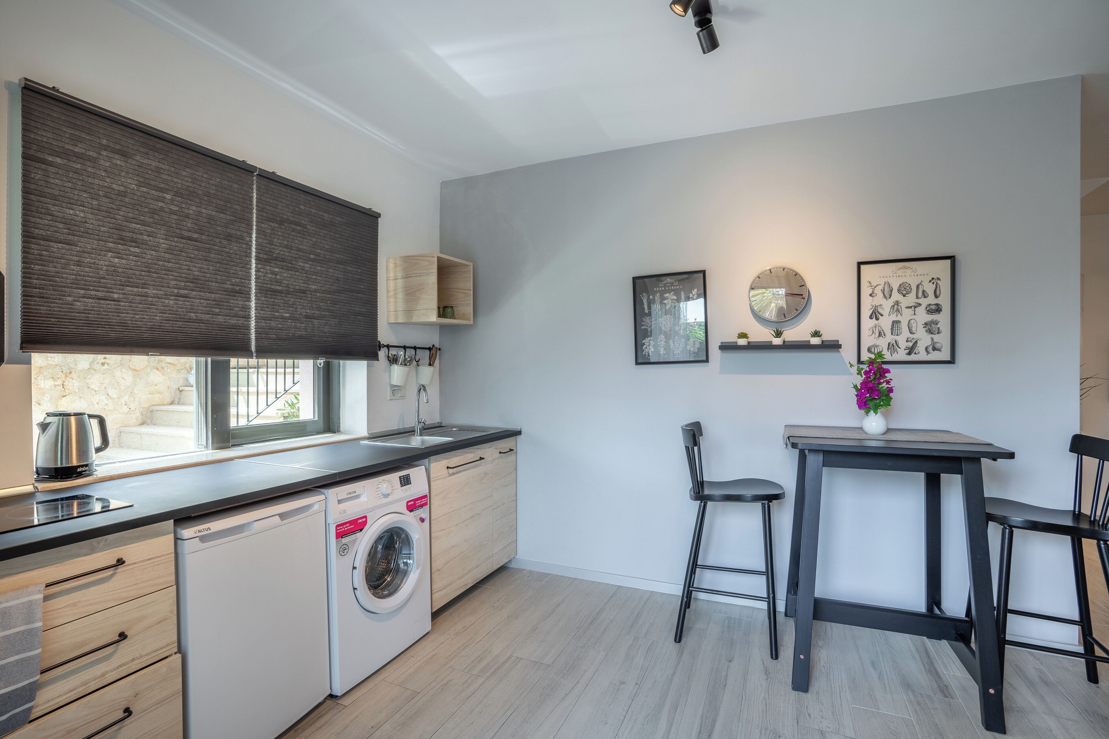 Una cocina compacta con lavadora, un lavamanos y un comedor con mesa y sillas.