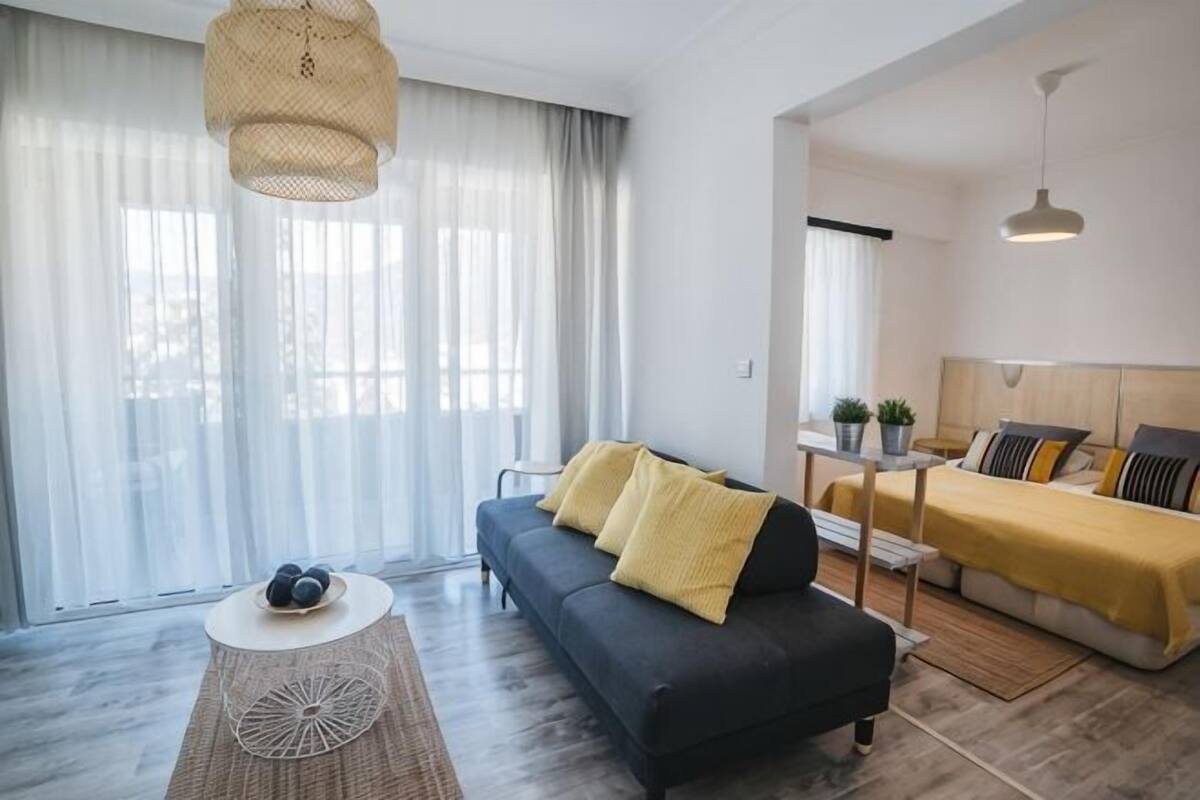 Una sala moderna con un sofá, una mesa de centro y una cama con una colcha amarilla.