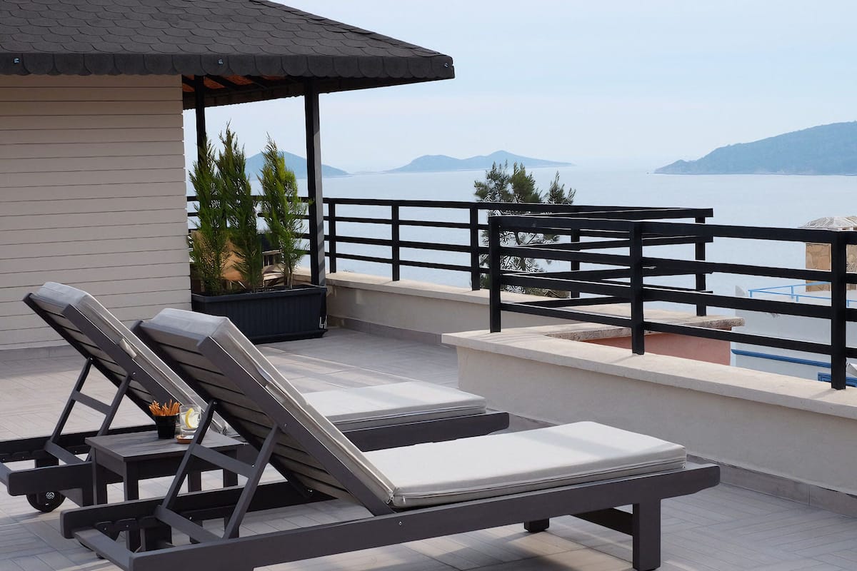 Una terraza en la azotea con dos sillones, una mesita y vistas al mar y a las montañas.