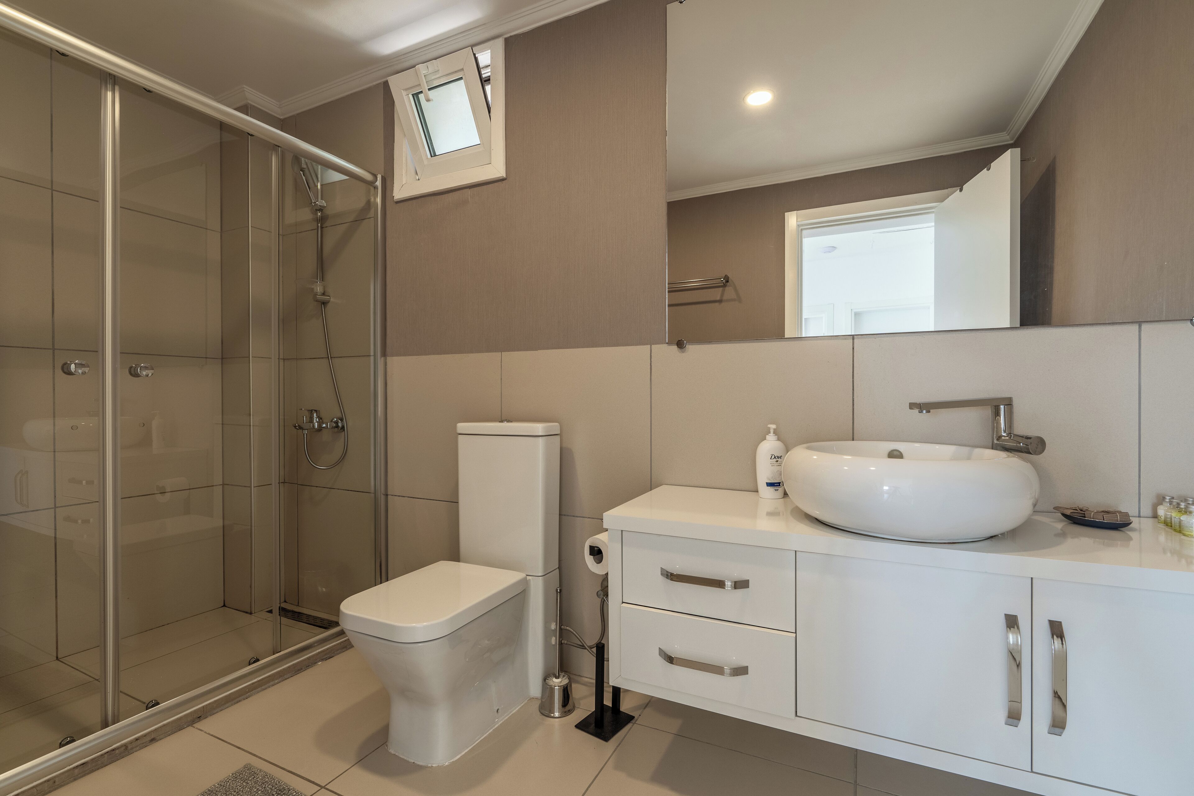 Une salle de bain moderne avec une douche à parois de verre, des toilettes, un lavabo et un meuble-lavabo avec des tiroirs.
