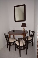 Un comedor con una mesa redonda, cuatro sillas, una lámpara y un espejo en la pared.