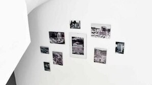 Una escalera de diseño moderno que conduce a una zona de descanso con una pared blanca decorada con fotografías en blanco y negro.