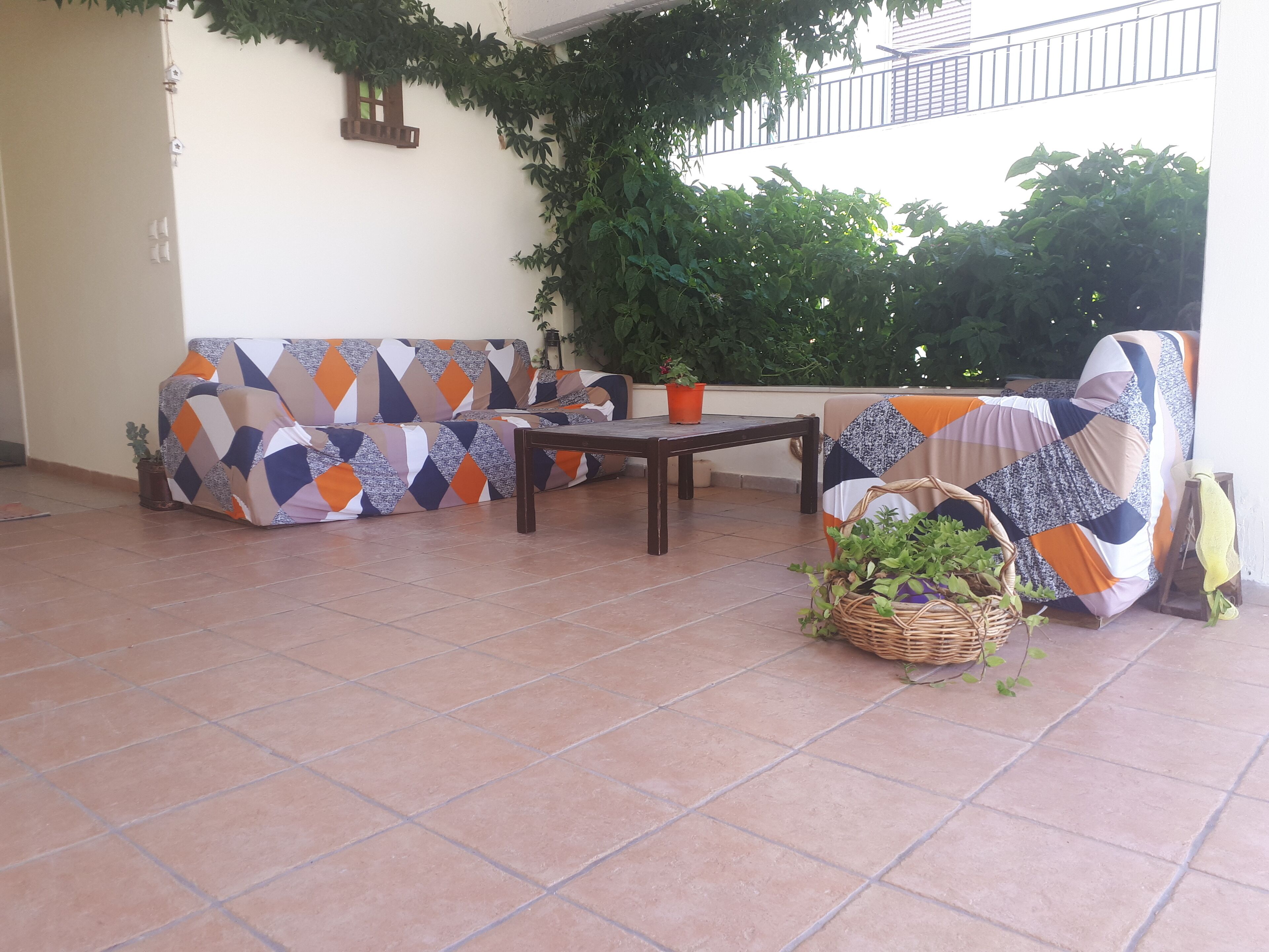Un patio con un sofá estampado, una mesa de madera y plantas en macetas.