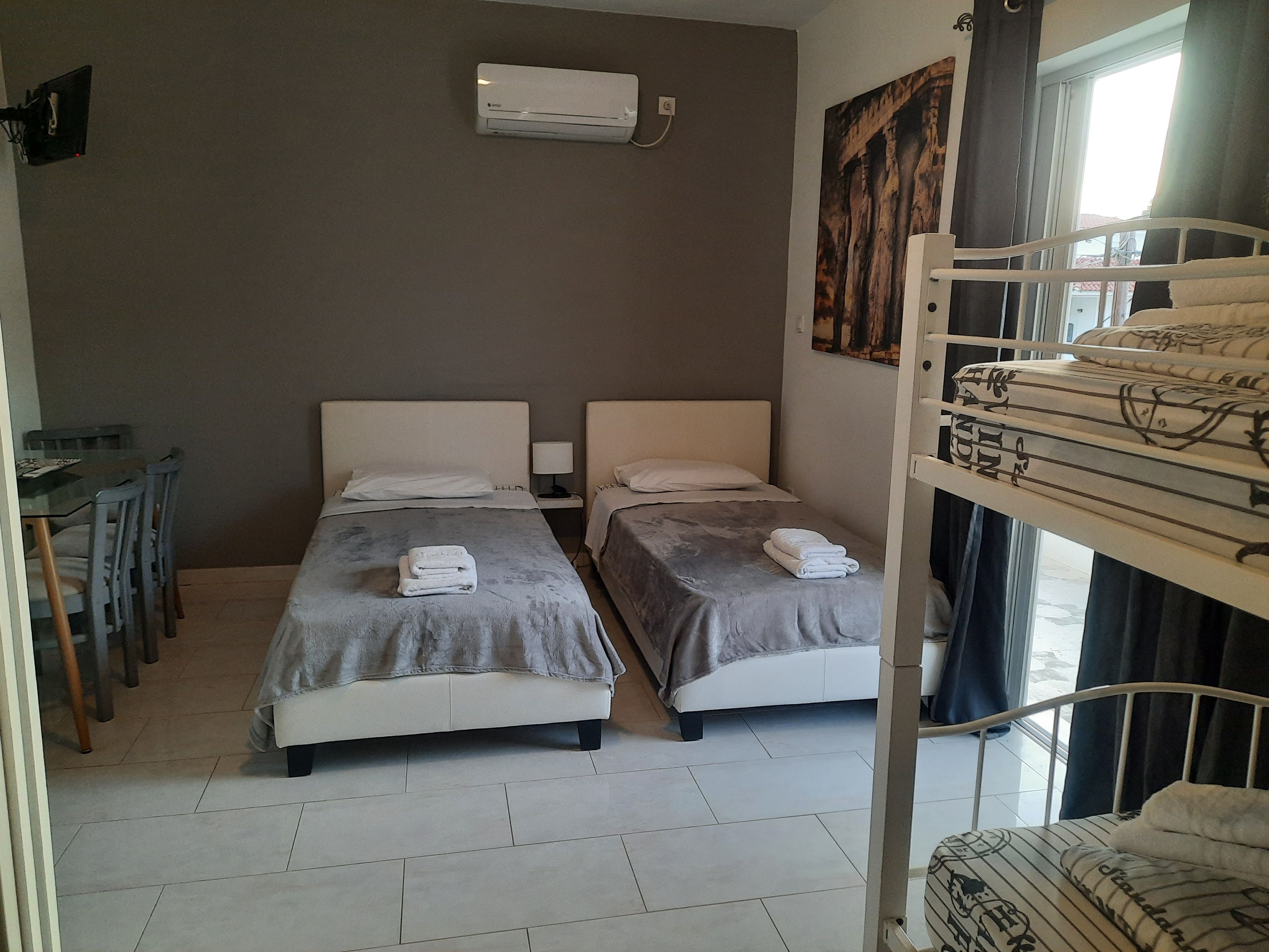 A room with two single beds, a dining table with chairs, and a bunk bed.