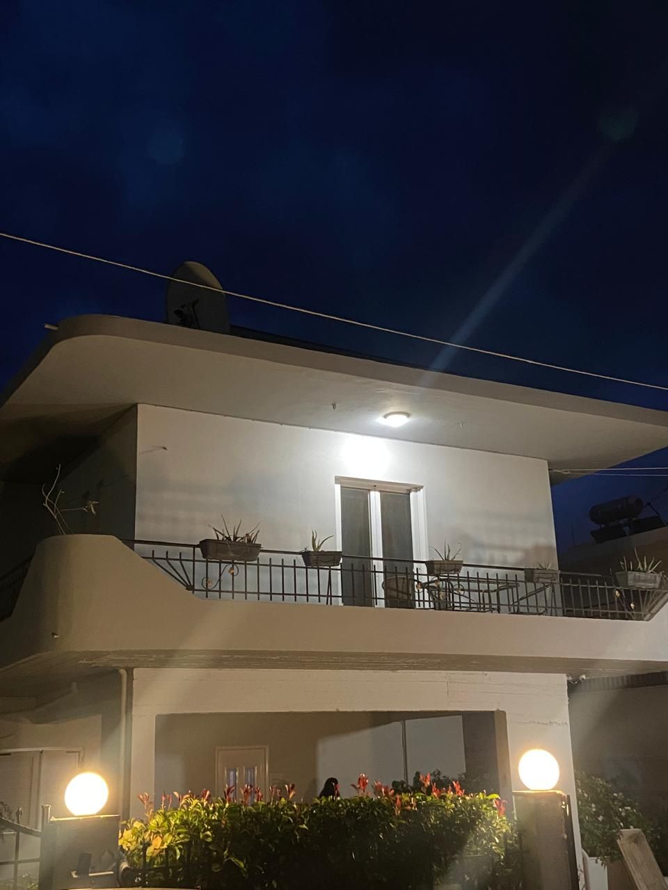 A two-story building with a balcony, a door, and a window.