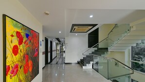 A modern interior with a glass staircase, a large abstract painting, and a clean, polished floor. - Hotel Imperial Villa (New Delhi)