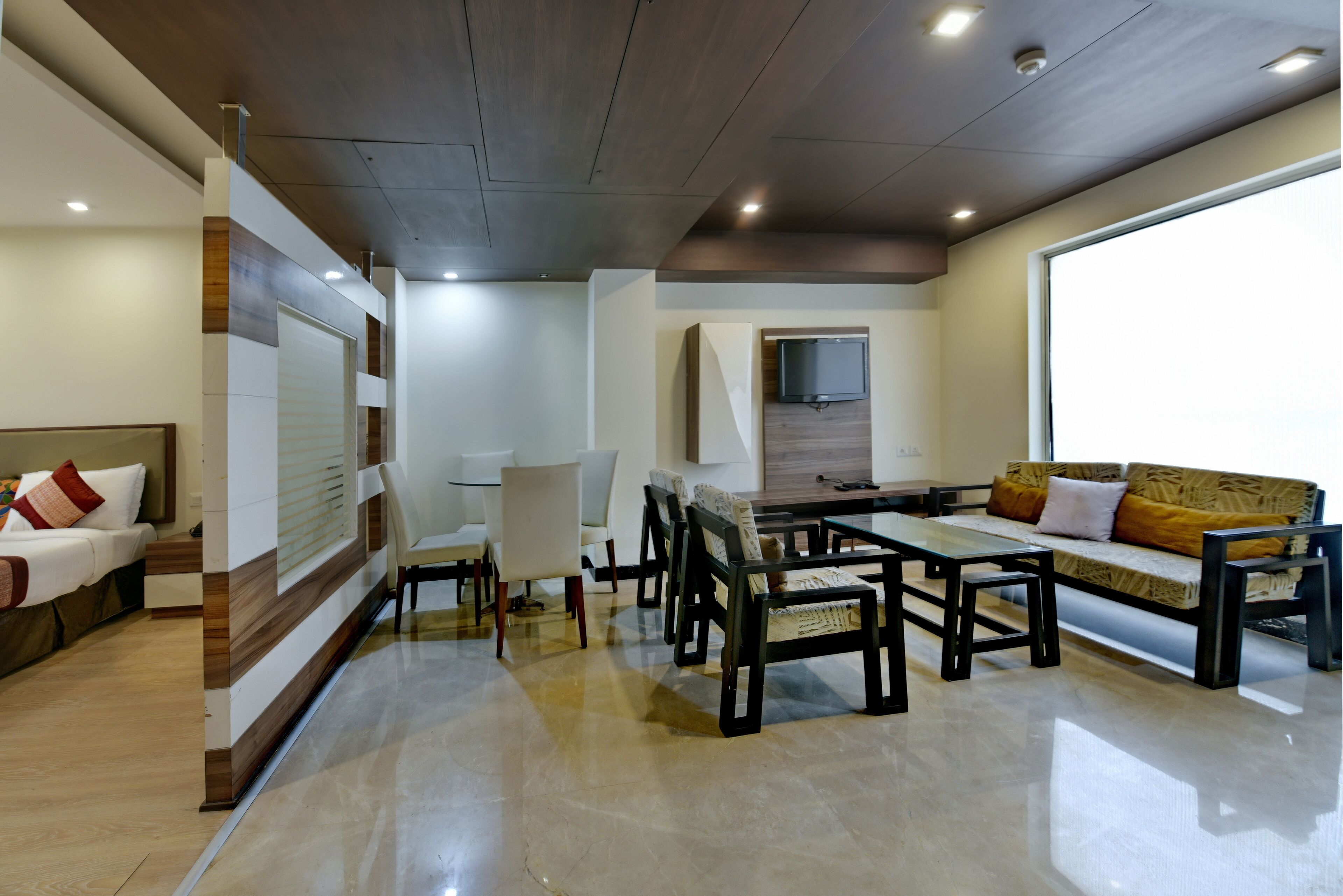 A modern living room with a sofa, chairs, a coffee table, and a TV mounted on the wall.