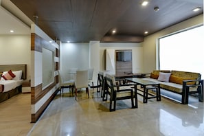 A modern living room with a sofa, chairs, a coffee table, and a TV mounted on the wall. - Hotel Imperial Villa (New Delhi)