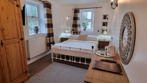 A bedroom with a bed, bedside tables, a wooden wardrobe, a radiator, a patterned rug, and a large mirror. - Lane Head Farm Country Guest House (Penrith)