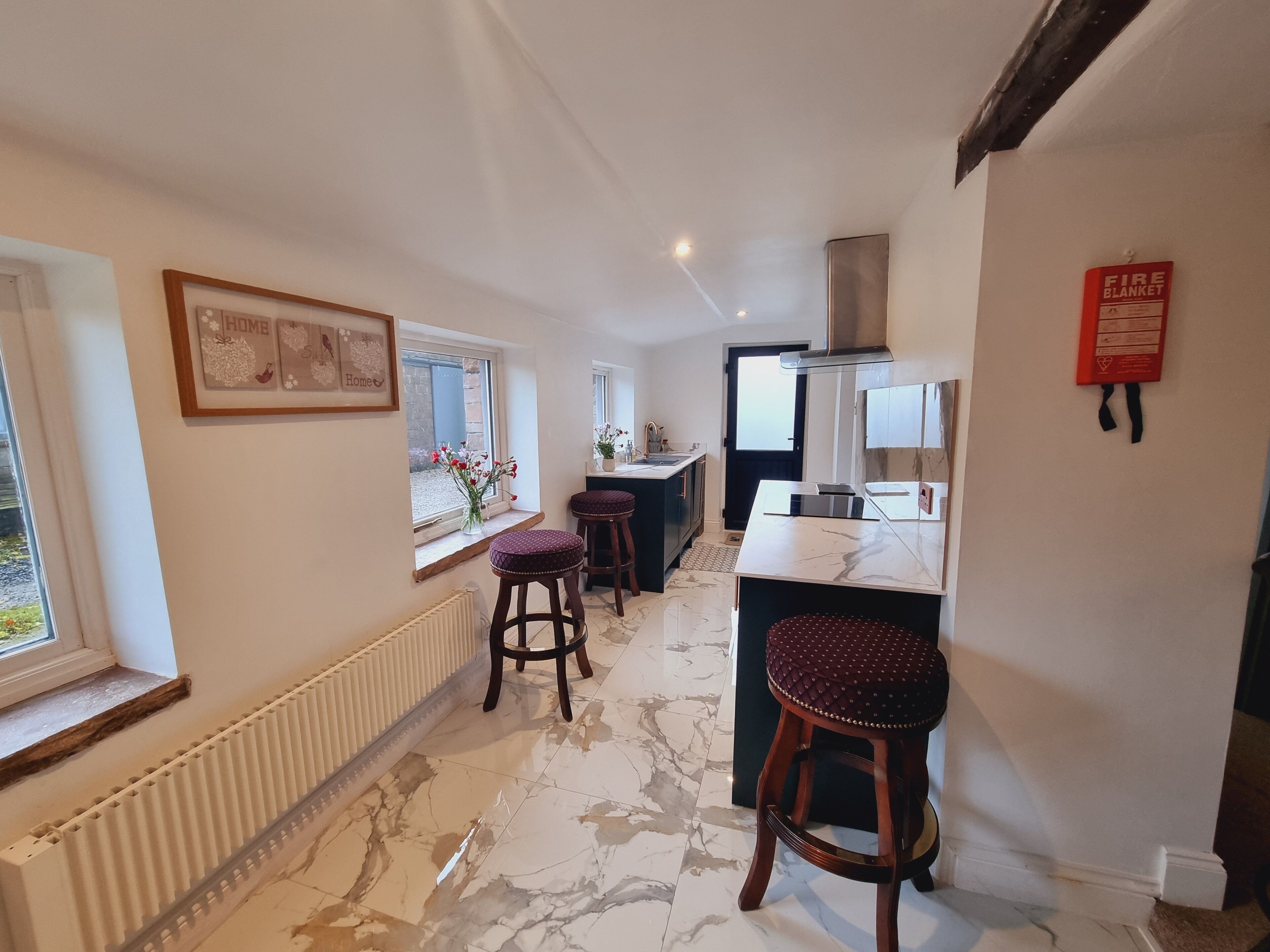 A modern kitchen with marble flooring, a central island, and two bar stools.