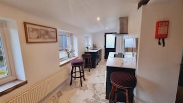 A modern kitchen with marble flooring, a central island, and two bar stools.