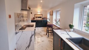 A modern kitchen with marble flooring, a built-in stove, and a large window providing natural light. - Lane Head Farm Country Guest House (Penrith)