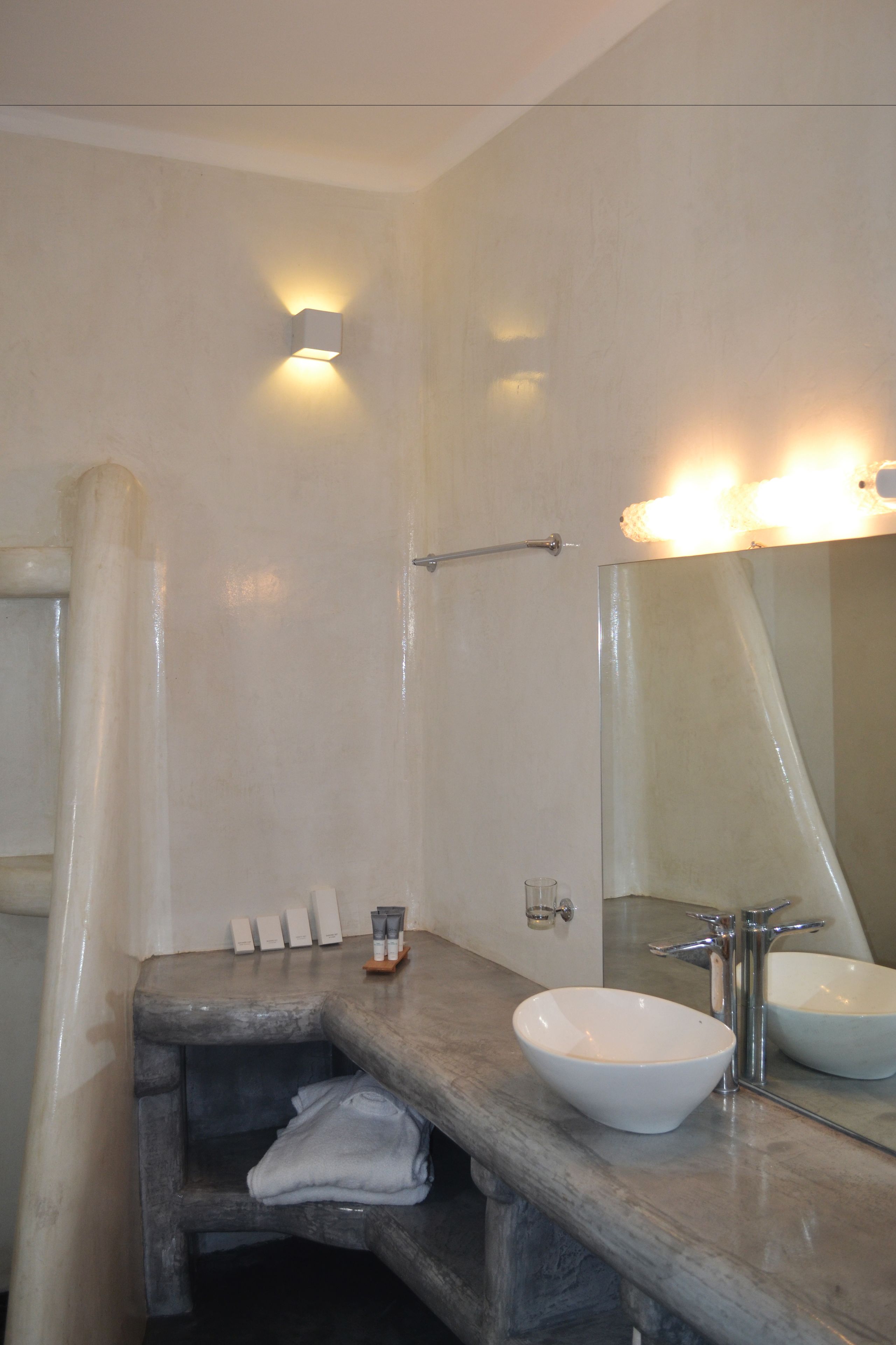 A bathroom with a stone sink, a mirror, and a towel rack.