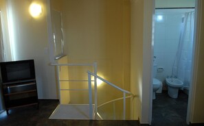 A staircase leading to a bathroom with a toilet and sink. - Complejo Barraquero (Mendoza)