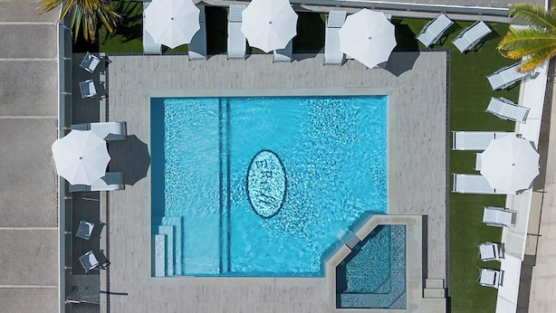 A rooftop pool with a rectangular shape, surrounded by white umbrellas and lounge chairs. - Hotel Ervill (Rimini)