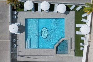 A rooftop pool with a rectangular shape, surrounded by white umbrellas and lounge chairs. - Hotel Ervill (Rimini)