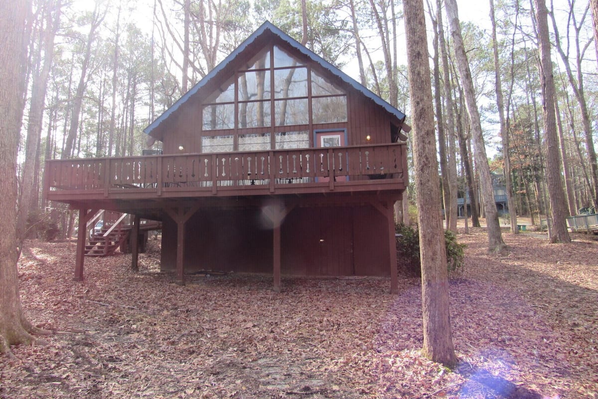 A cabin with a balcony, surrounded by trees.