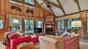 A cozy room with a wooden ceiling, a fireplace, and a red sofa. - Pine Mountain Club Chalets Resort (Pine Mountain)