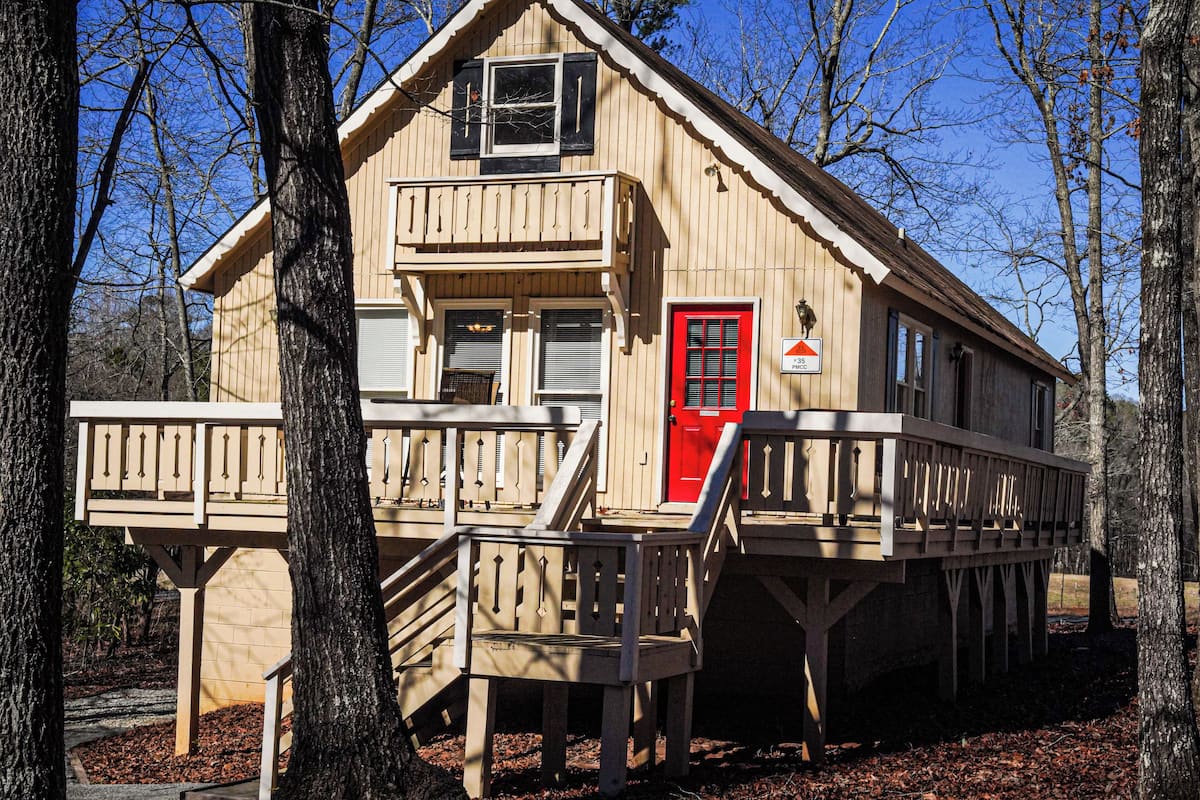 A wooden cabin with a red door, a balcony, and a sign indicating a price of $15.