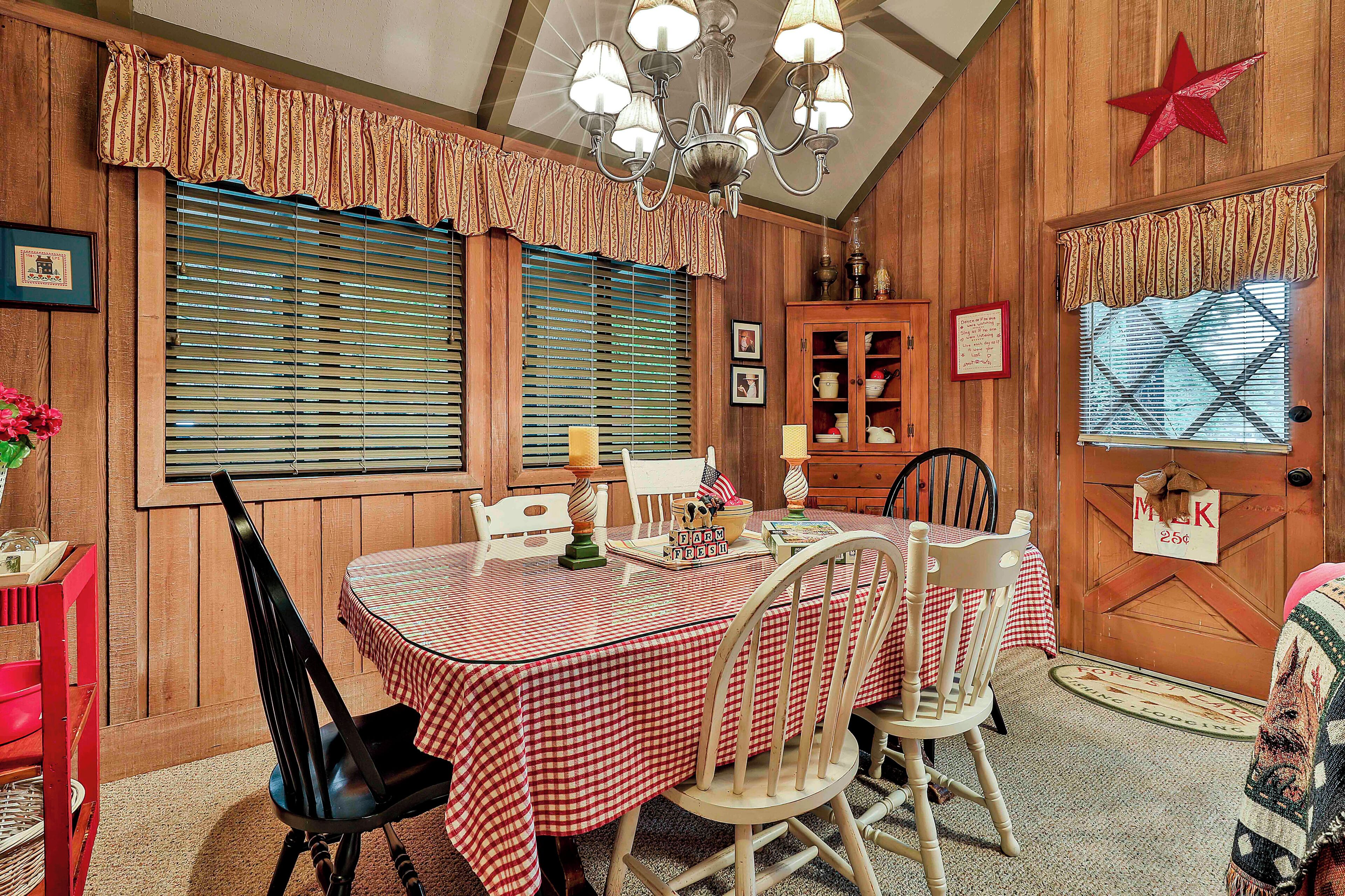 A dining area with a table set for four, wooden paneled walls, a chandelier, and a red star decoration.