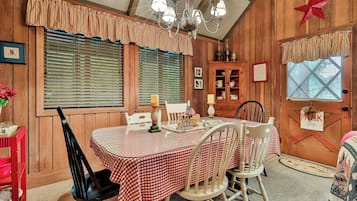 A dining area with a table set for four, wooden paneled walls, a chandelier, and a red star decoration.