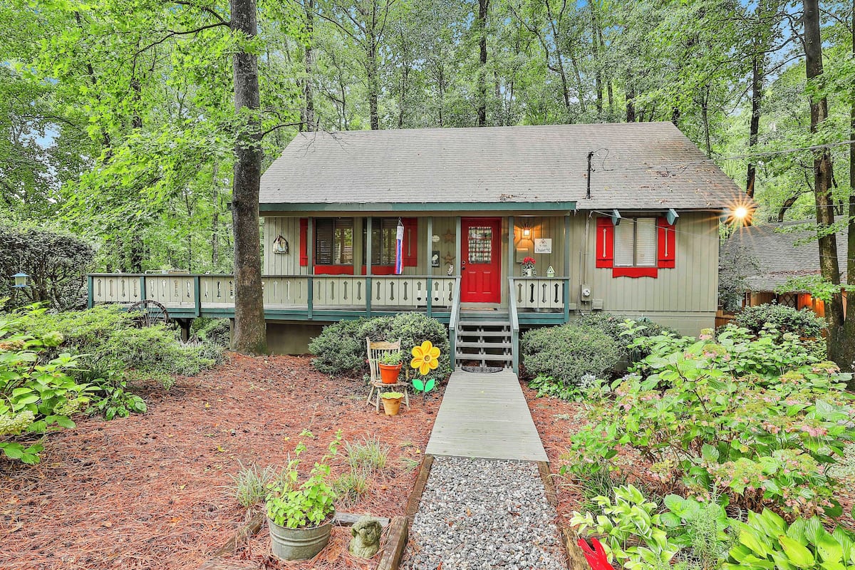 A house with a red door, a porch, and a wooden pathway leading to the entrance.