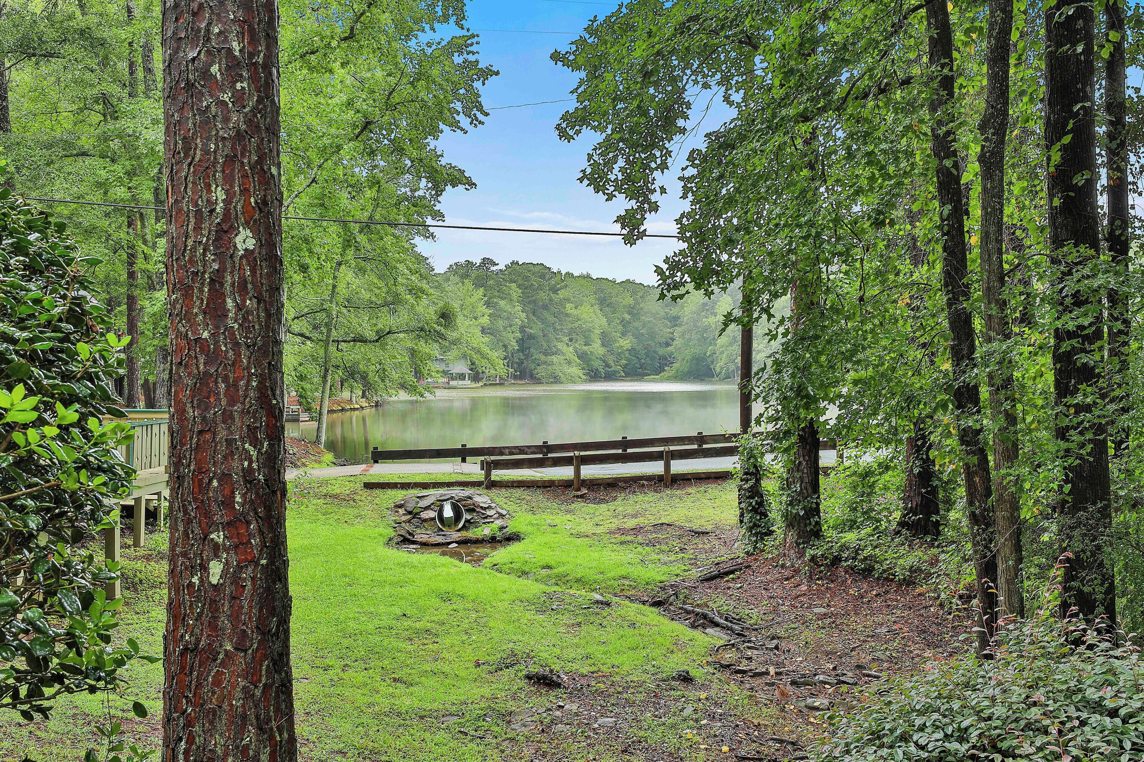 Une zone boisée avec un lac, une terrasse en bois et une construction en pierre.