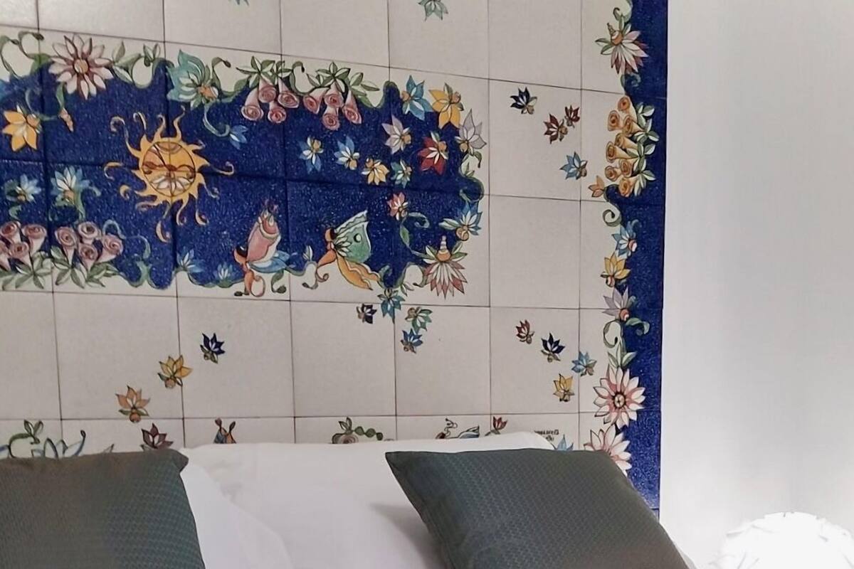 Una cama con cabecera floral, dos almohadas y un libro sobre la cama.