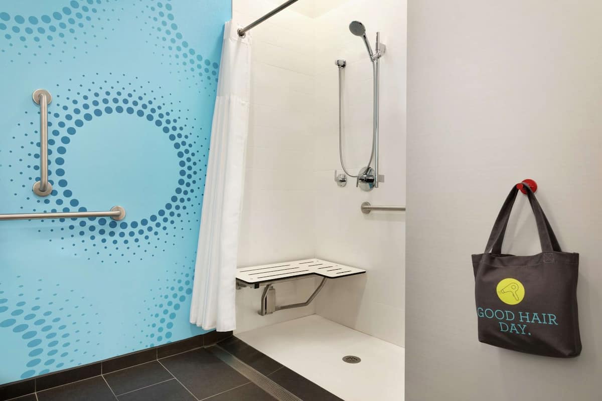 A bathroom with a shower, a handrail, a grab bar, and a towel rack.