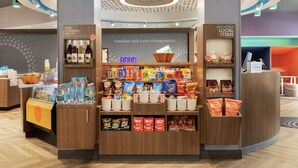Uma área de pequeno-almoço com diversas opções de comida e bebida, incluindo cereais, snacks e água engarrafada.