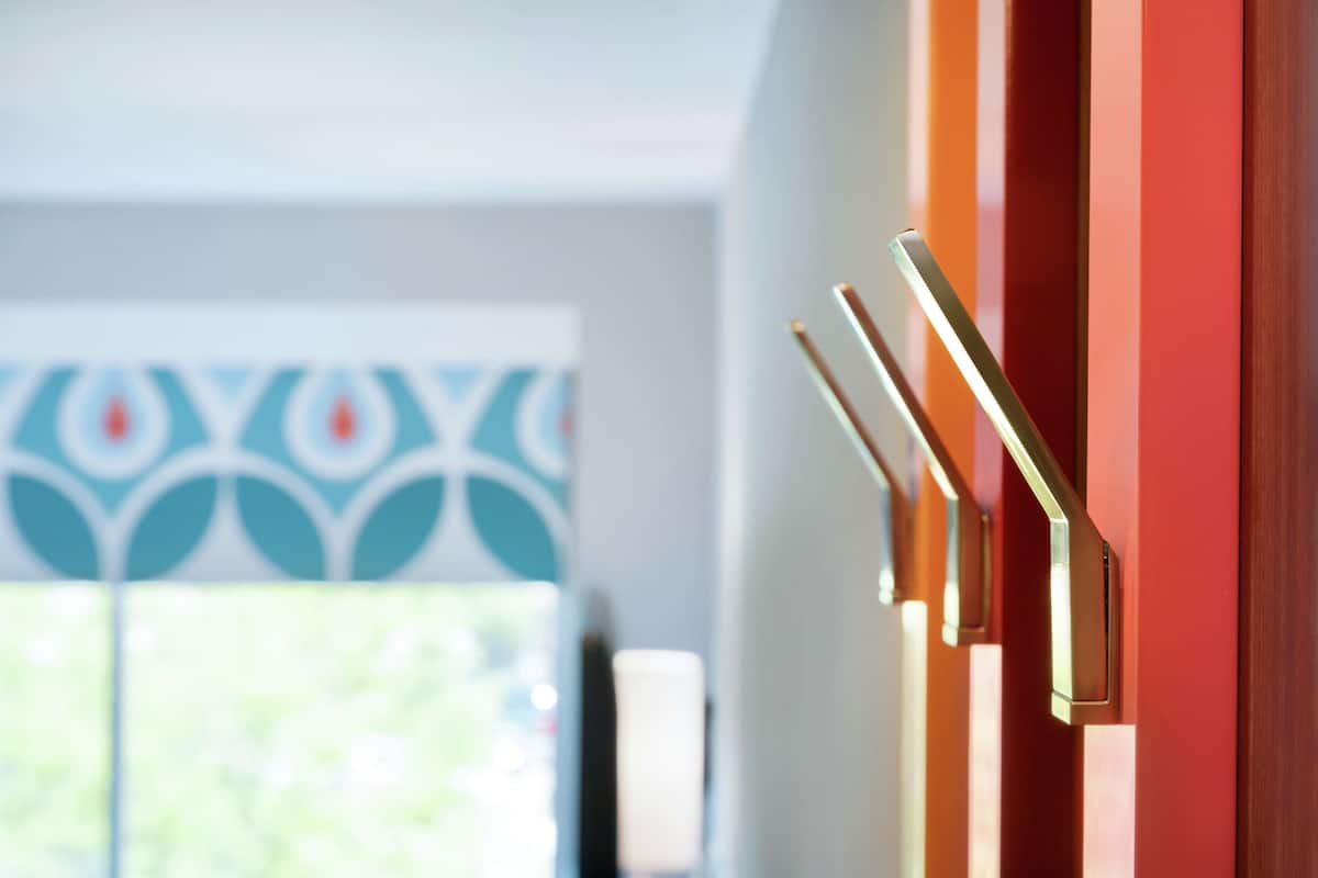 A close-up of a door with a modern handle and a patterned wall in the background.