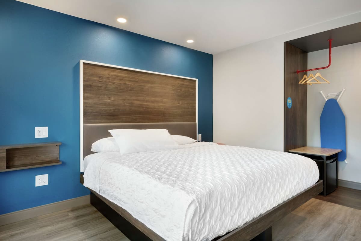 A modern bedroom with a large bed, built-in shelving, and a blue accent wall.