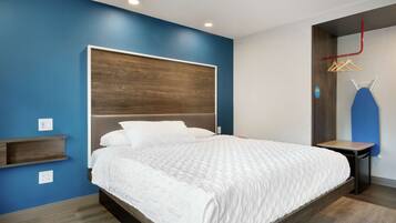 Un dormitorio moderno con una cama grande, estanterías empotradas y una pared azul decorativa.