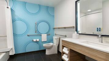A modern bathroom with a blue wall, a white toilet, a sink with a mirror, and a towel rack.