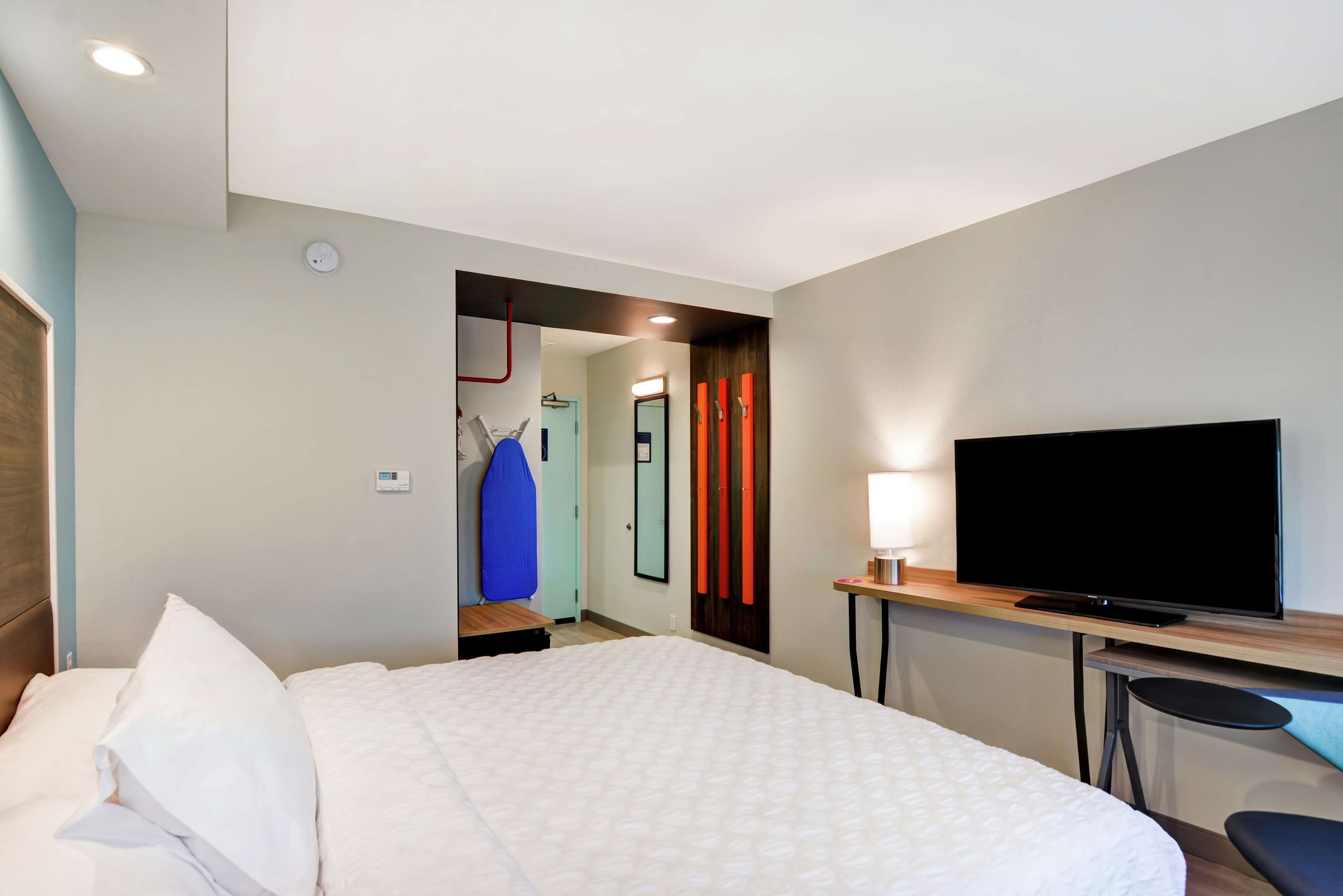 A hotel room with a bed, a television, a desk, and a chair.