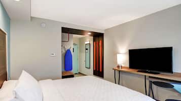 A hotel room with a bed, a television, a desk, and a chair.