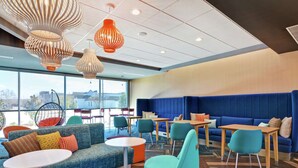 A modern lounge area with seating arrangements, tables, and hanging pendant lights. - Tru by Hilton Baton Rouge Citiplace, LA (Baton Rouge)