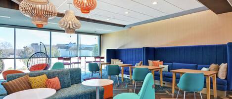 A modern lounge area with seating arrangements, tables, and hanging pendant lights.