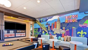 A pool table area with a vibrant mural of New Orleans, including the name 'BATON ROUGE'. - Tru by Hilton Baton Rouge Citiplace, LA (Baton Rouge)