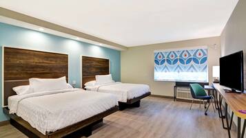 A hotel room with two beds, a desk, a chair, and a TV.