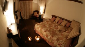 A bedroom with a large bed, a bedside table, a chair, and a lamp. - Nastou View Hotel (Sintiki)