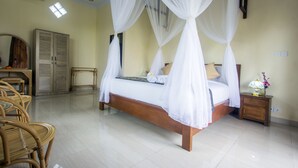 A bedroom with a four-poster bed, wooden furniture, and a small bedside table with a lamp. - Purnama Guest House (Ubud)