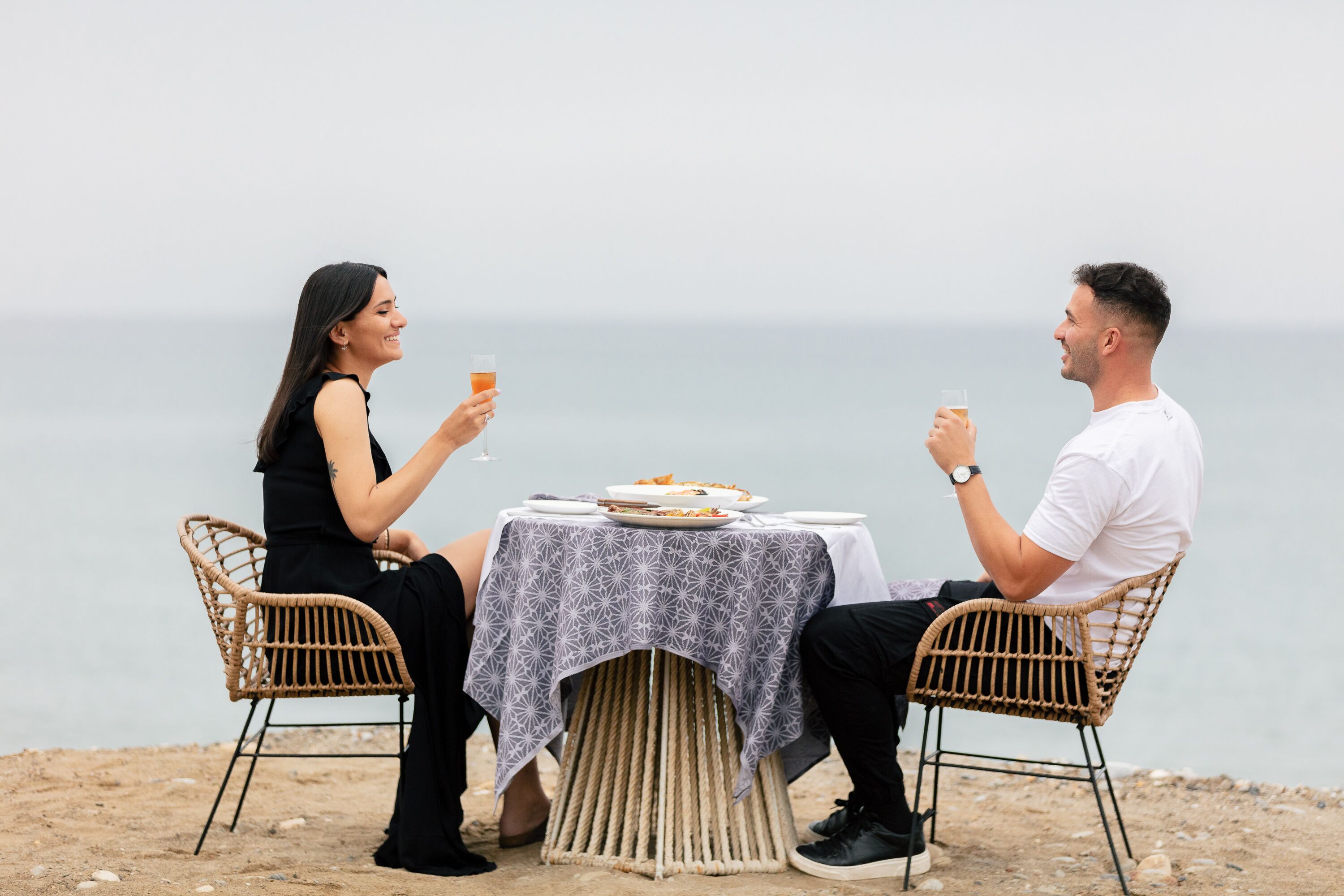 Two people dining at a table with a view of the sea.
