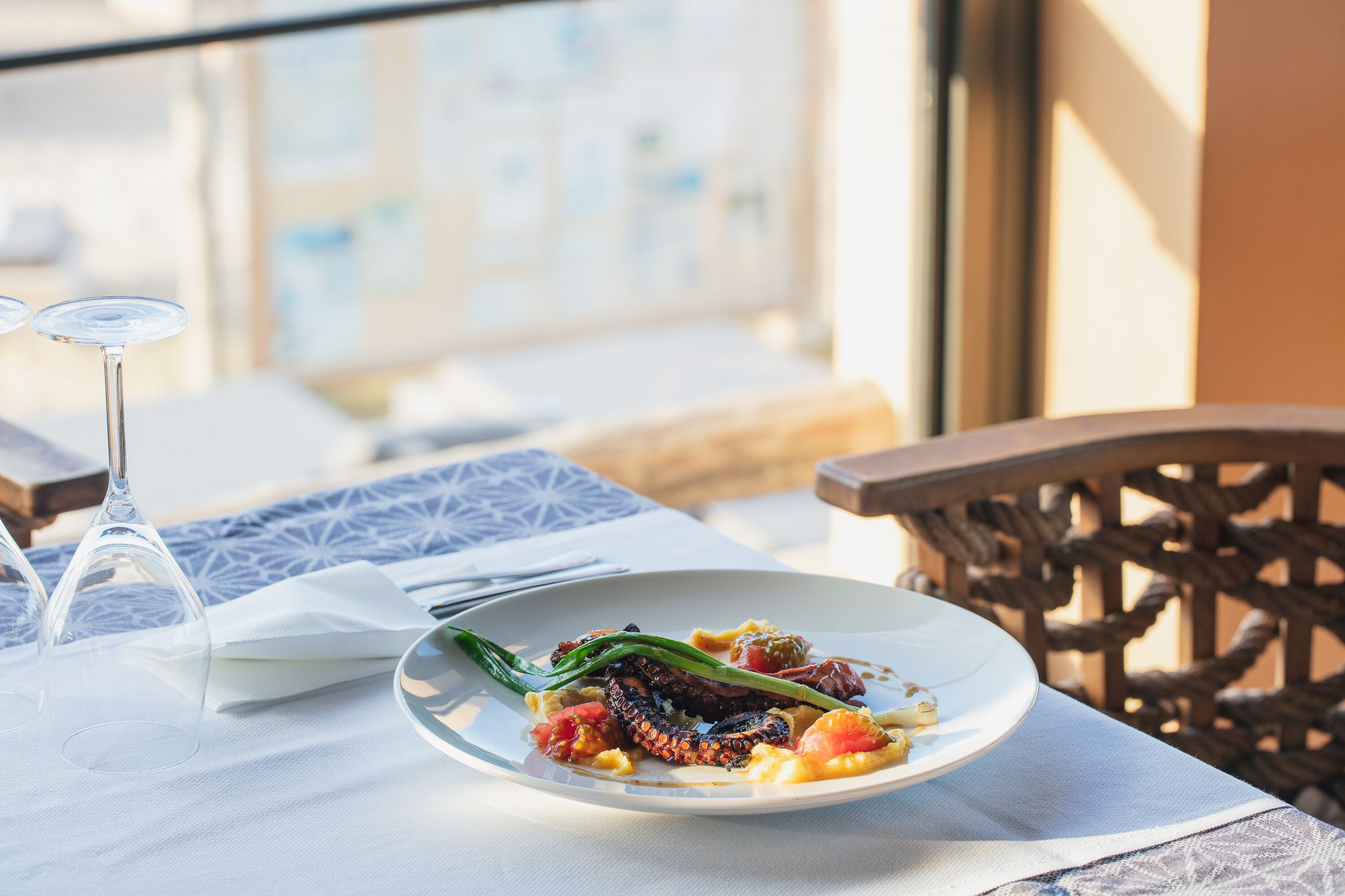 A dining table with a plate of food, a wine glass, and a napkin.