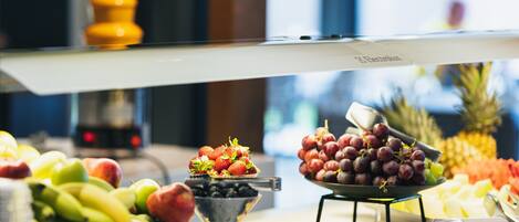 A buffet with various fruits and vegetables, including bananas, apples, and grapes.